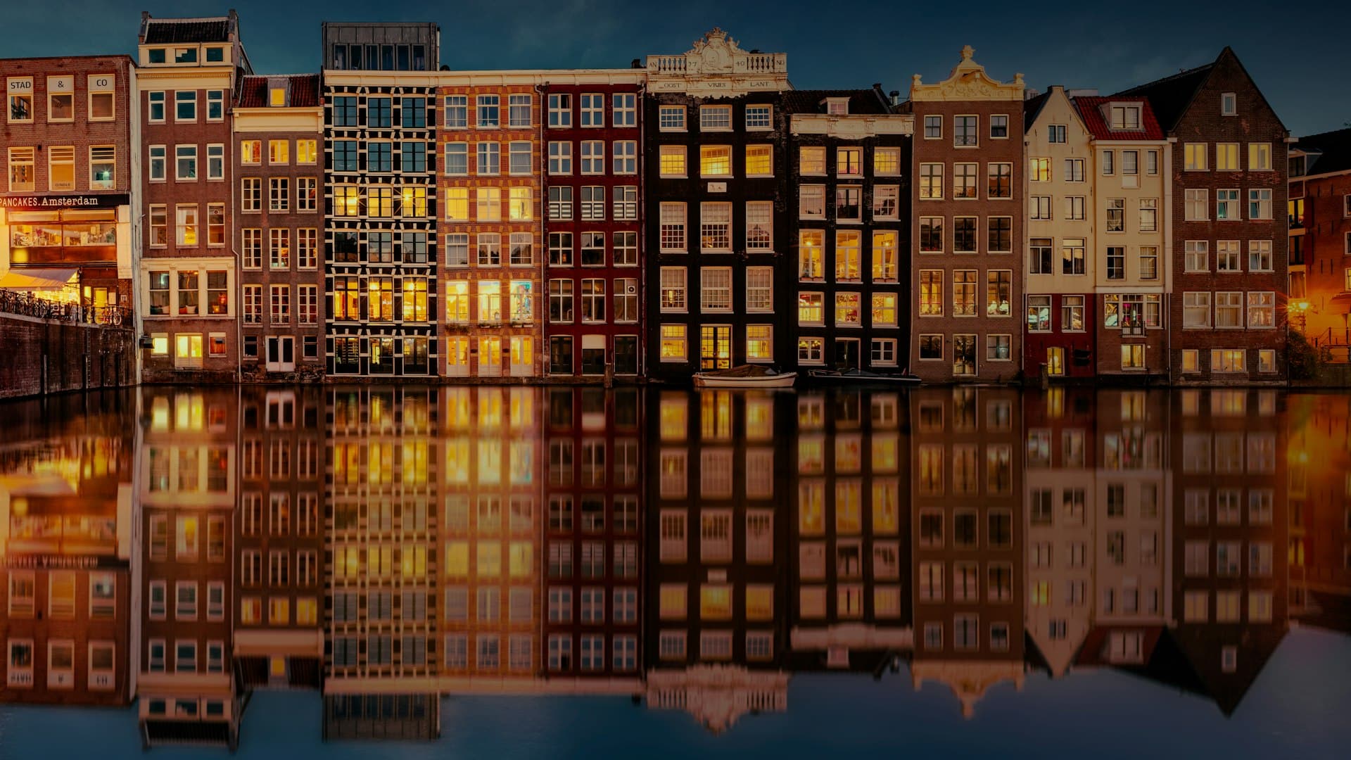 Amsterdam canal houses at golden hour with reflections in the water